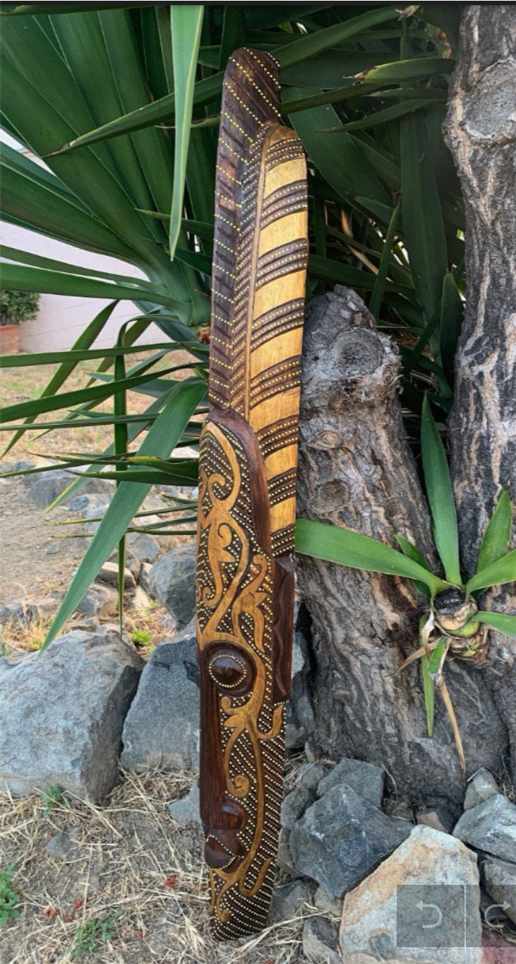 intricately carved wooden staff with dot patterns and scrolling designs leaning beside a tree