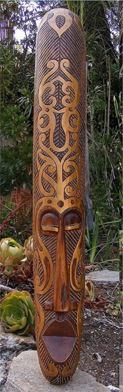 Intricately carved wooden tiki statue with geometric patterns and a carved face