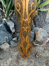 Intricately carved wooden tribal sculpture with yellow dotted patterns.