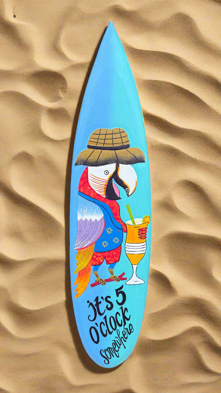 Blue surfboard artwork featuring a colorful toucan wearing a hat, holding a cocktail, and the caption 'It's 5 O'clock Somewhere'.
