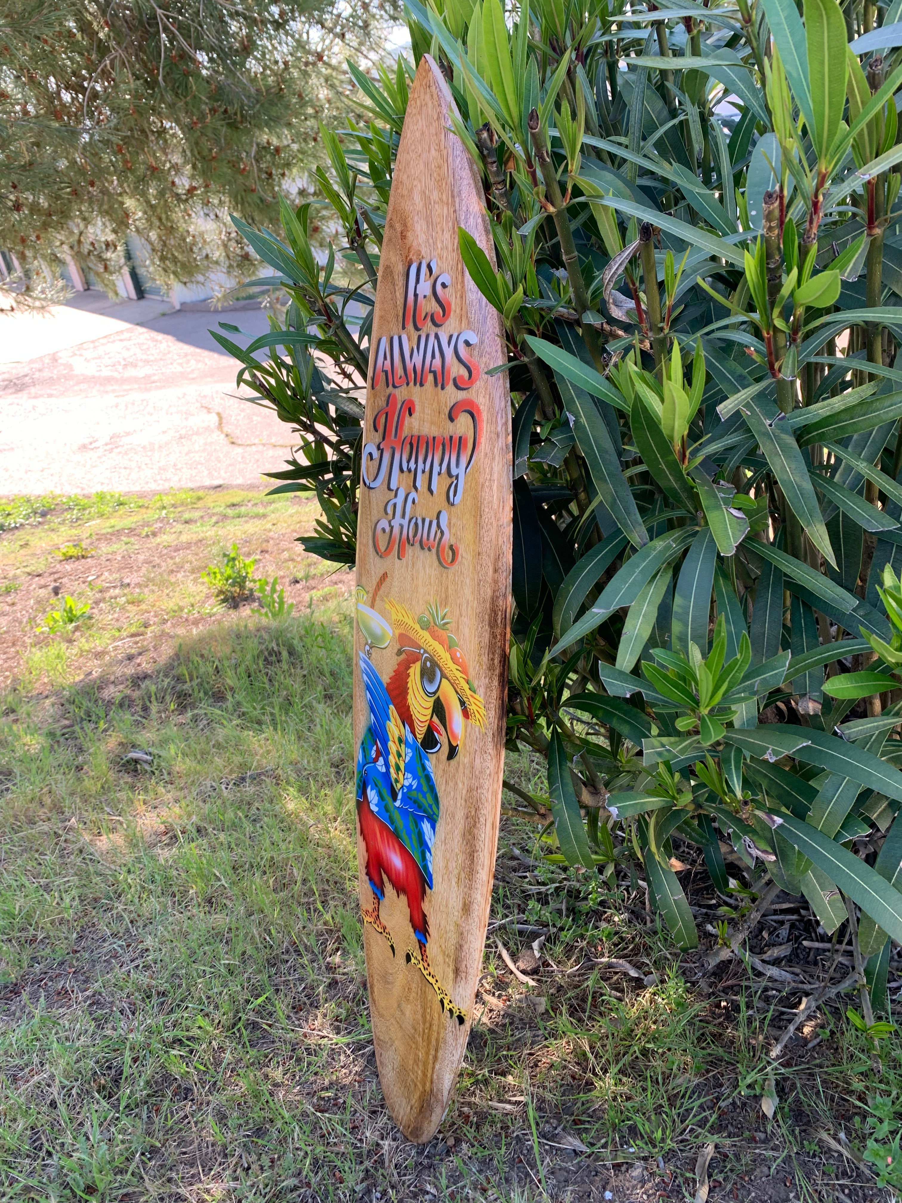 Wooden surfboard sign reads 'It's Always Happy Hour' with a bright parrot illustration