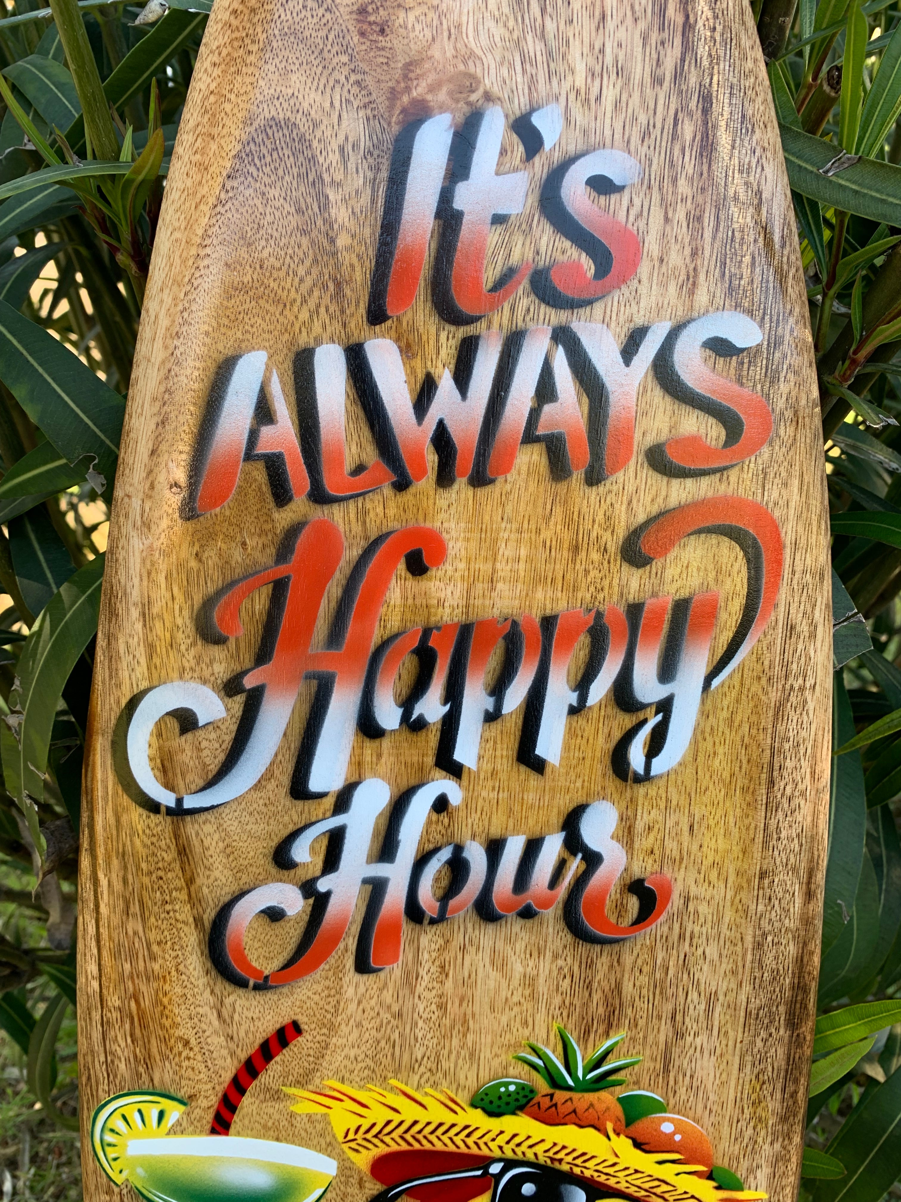 Wooden sign with colorful typography reading It's Always Happy Hour and tropical fruits at the bottom.