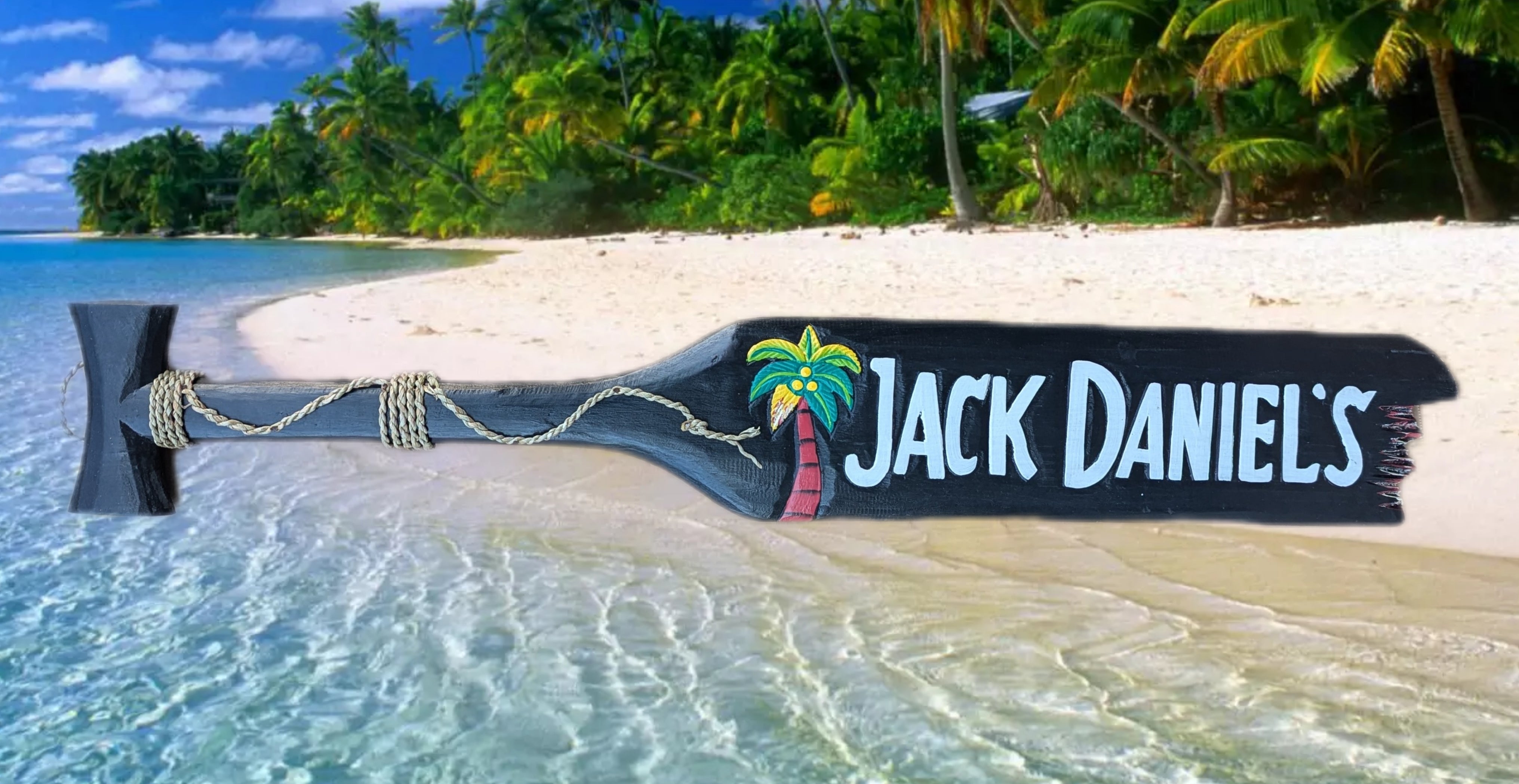 Wooden paddle sign reading Jack Daniel's on a tropical beach with palm trees and turquoise water.