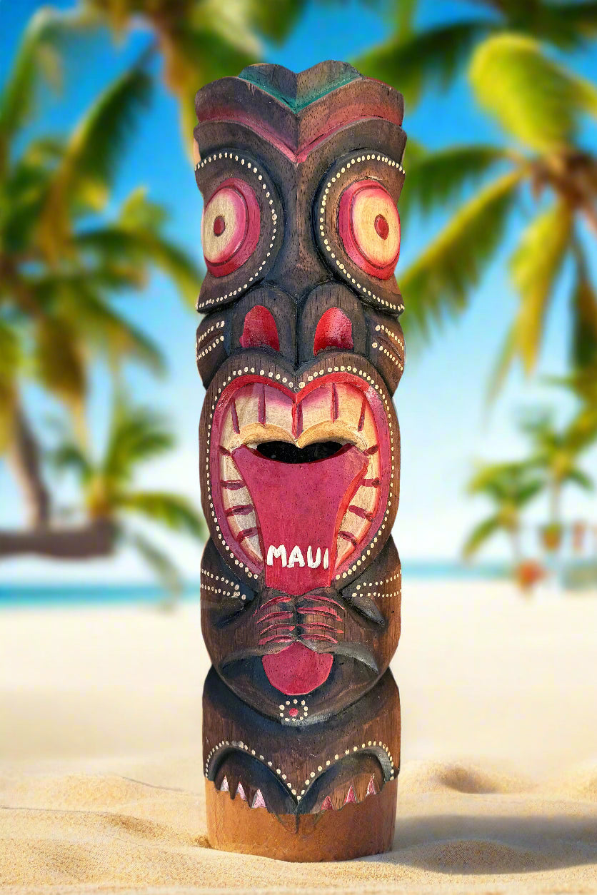 Maui tiki totem on a sandy beach with palm trees and clear blue sky