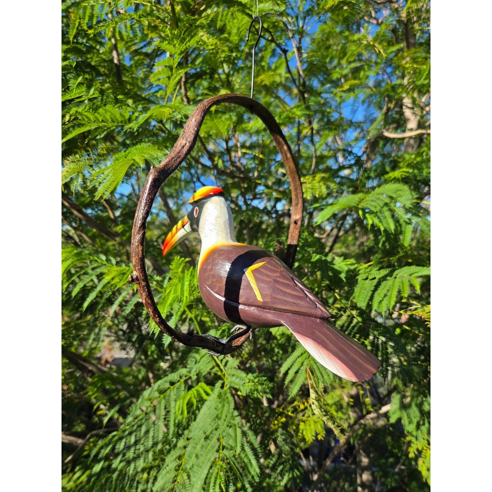 Decorative bird ornament hanging from a branch with a green leafy backgroun