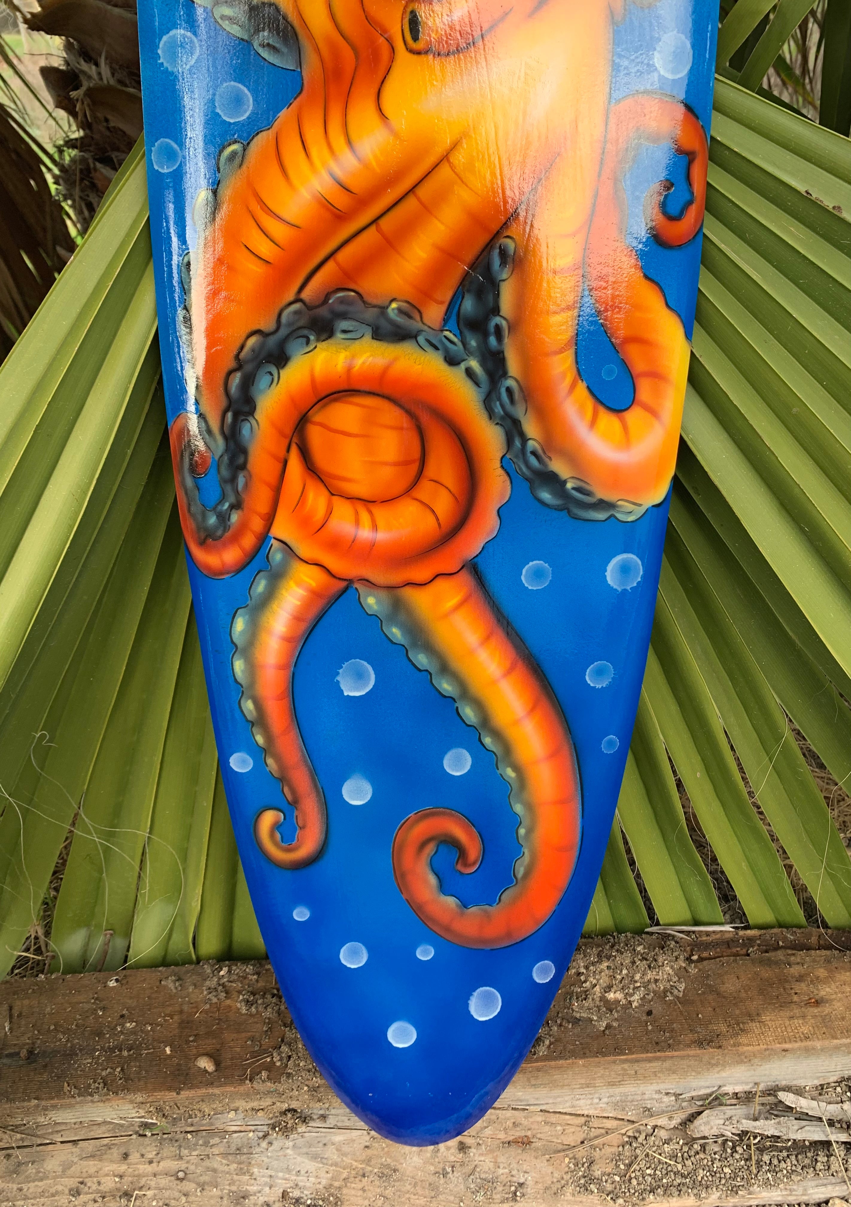 Orange seahorse artwork on a blue surfboard with white bubbles
