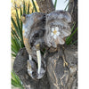 Carved elephant head on a tree trunk with white floral swirl patterns on the ears.