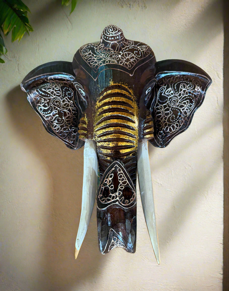 ornate elephant head wall sculpture with gold accents and carved lace patterns on ears