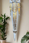Ornate white and gold decorative dagger sculpture with intricate carvings.