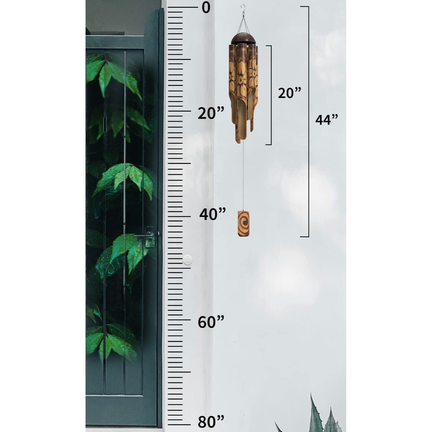 Outdoor wall-mounted inch ruler with a wooden wind chime hanging beside a green door.