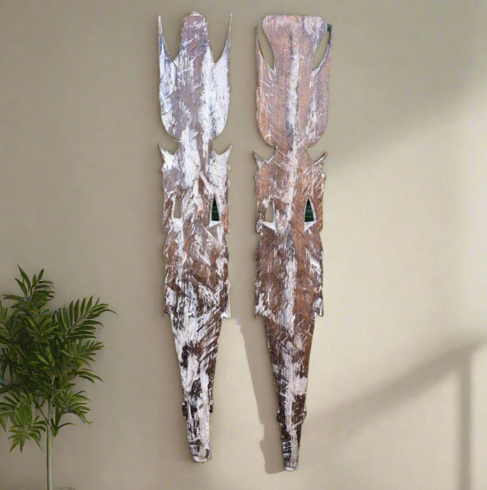 Pair of weathered wooden mask sculptures mounted on a wall