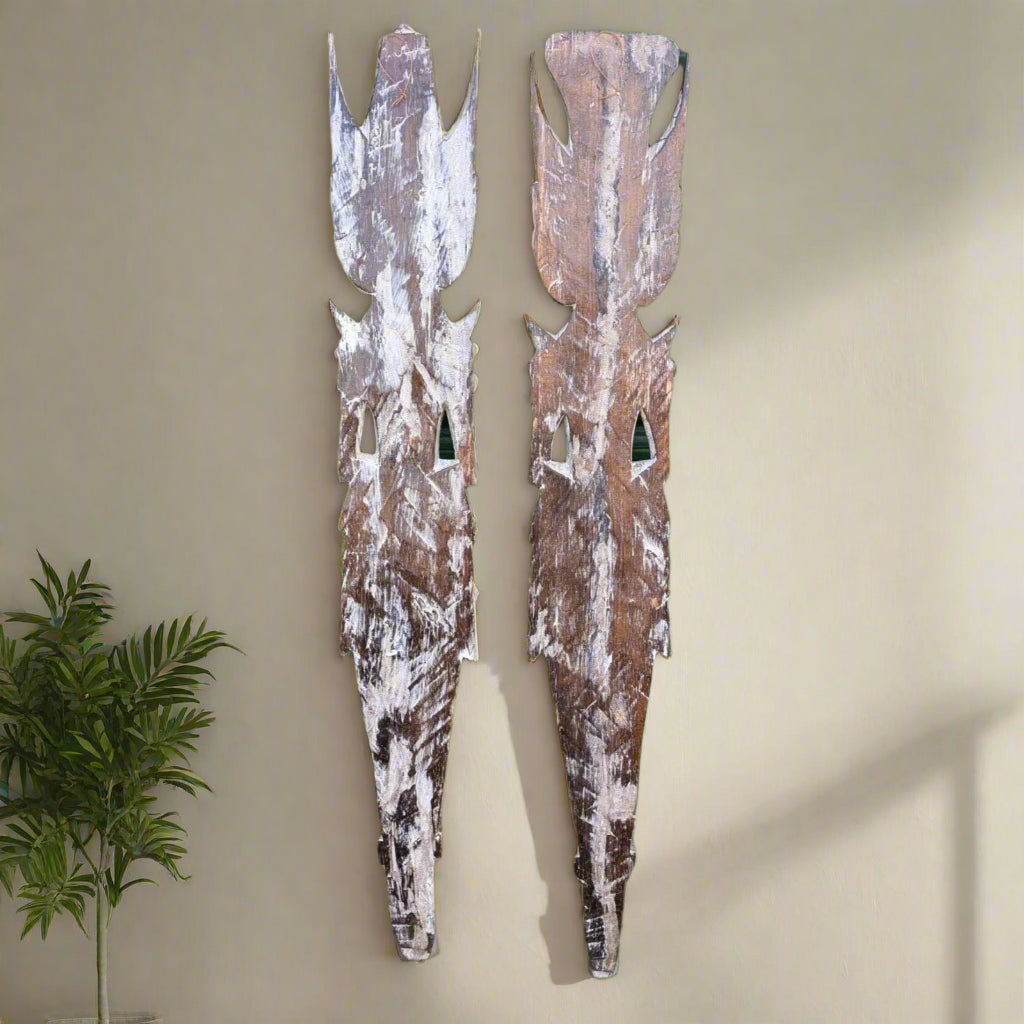pair of weathered wooden totem sculptures mounted on a beige wall