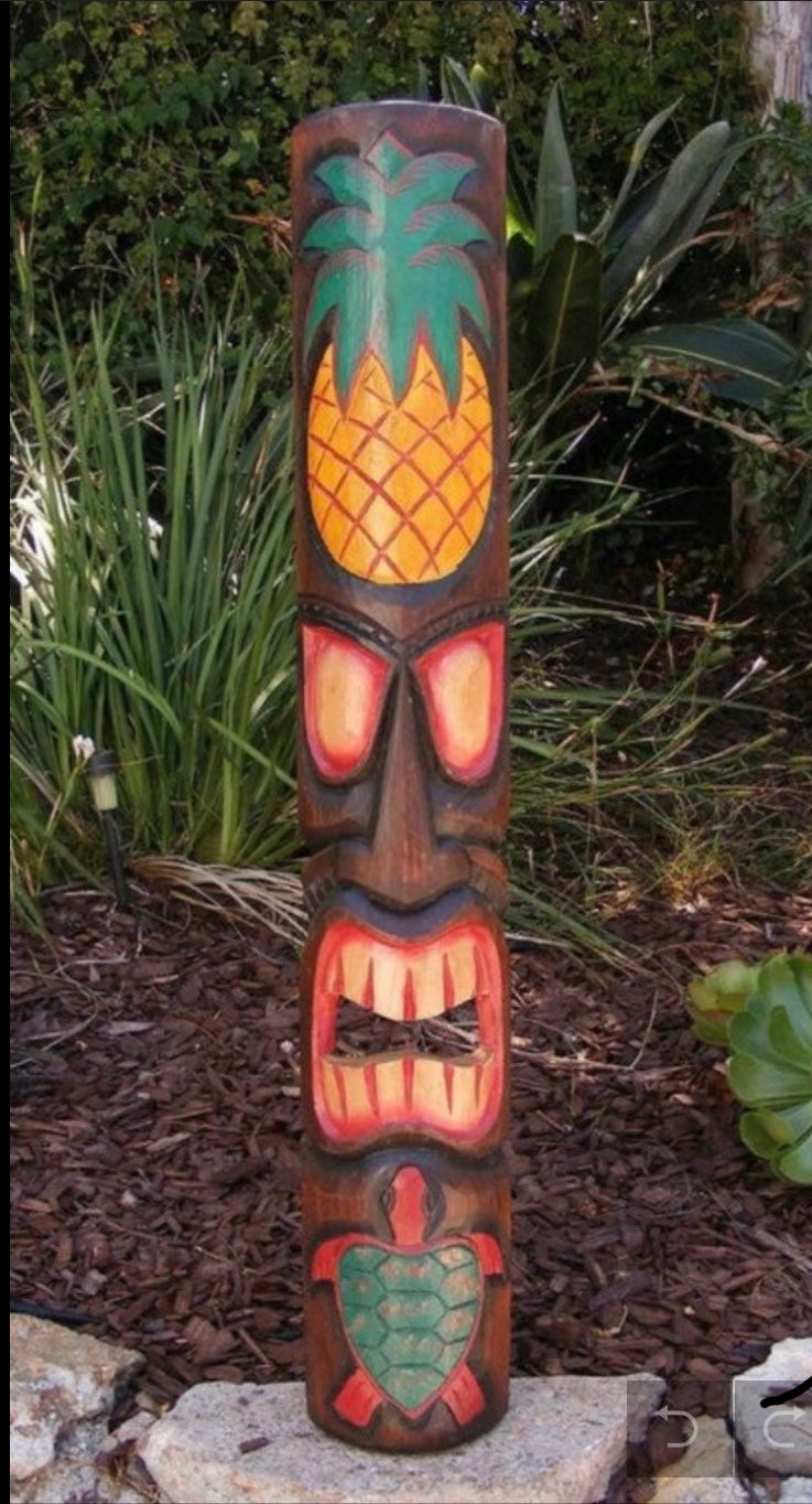carved wooden tiki totem with pineapple top in a garden