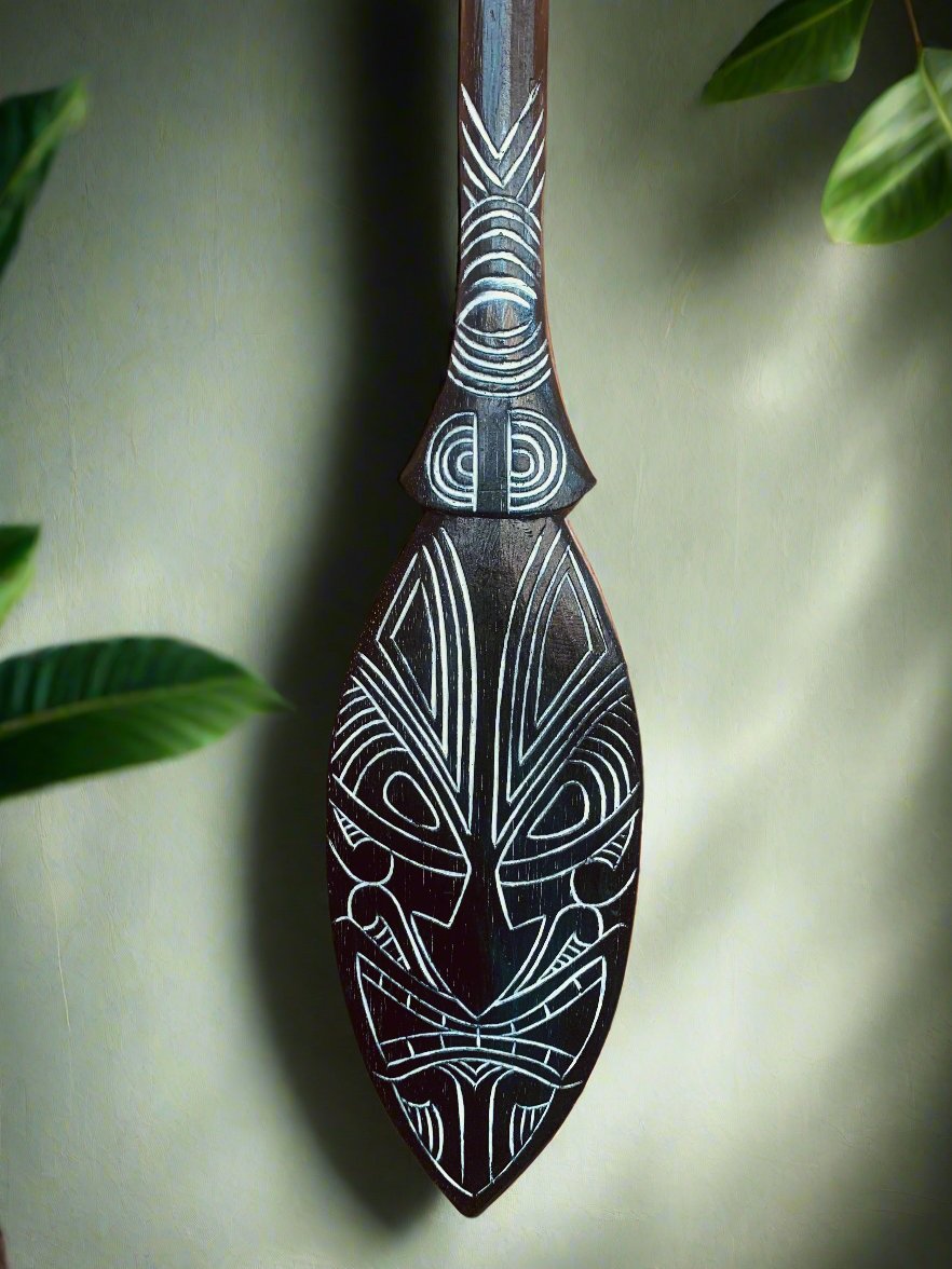 Polynesian tiki carving with geometric white patterns on dark wood