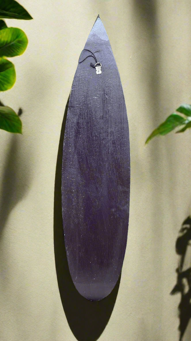 Purple wooden surfboard-shaped wall decor with a small pendant hanging at the top