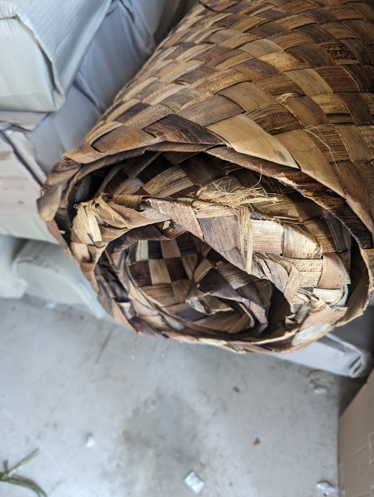 Close-up of a rolled, woven palm leaf mat in natural brown tones