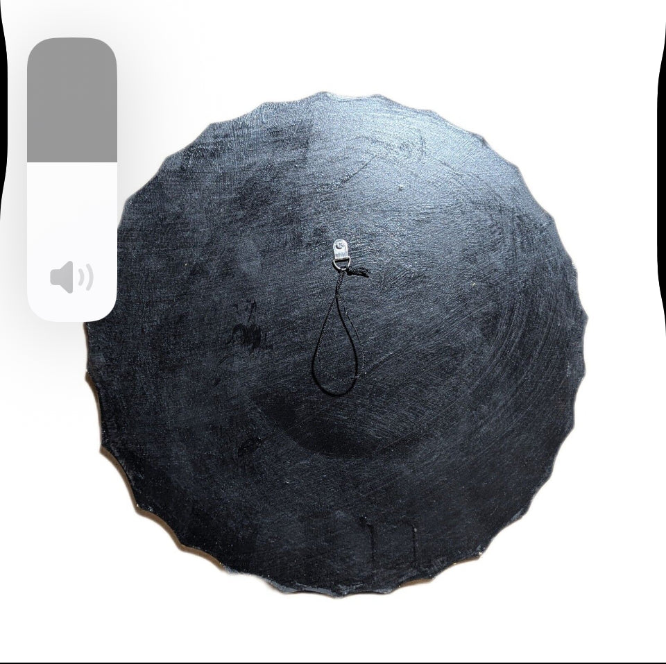 Top view of a round black slate plate with a metal hook and black cord loop at the center.