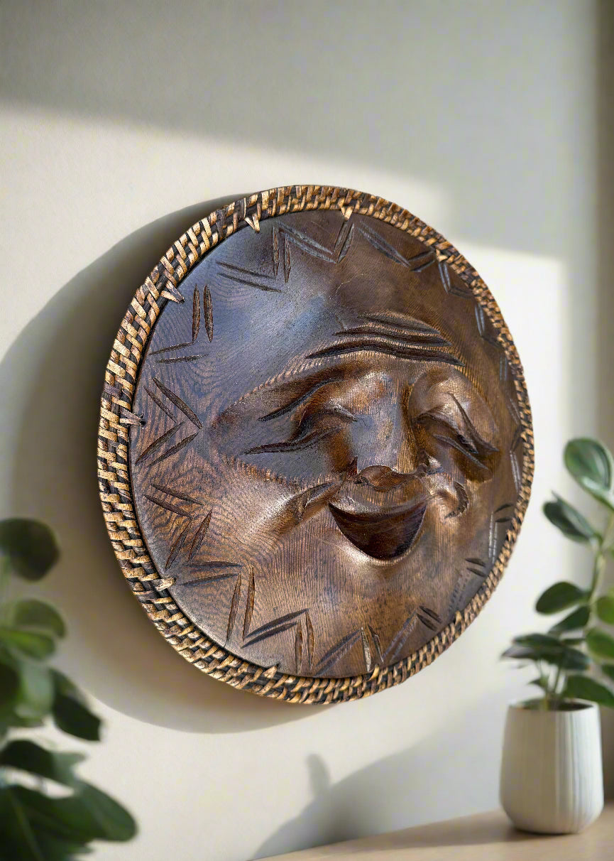 Round carved wooden wall art featuring a smiling sun-face with a woven border.
