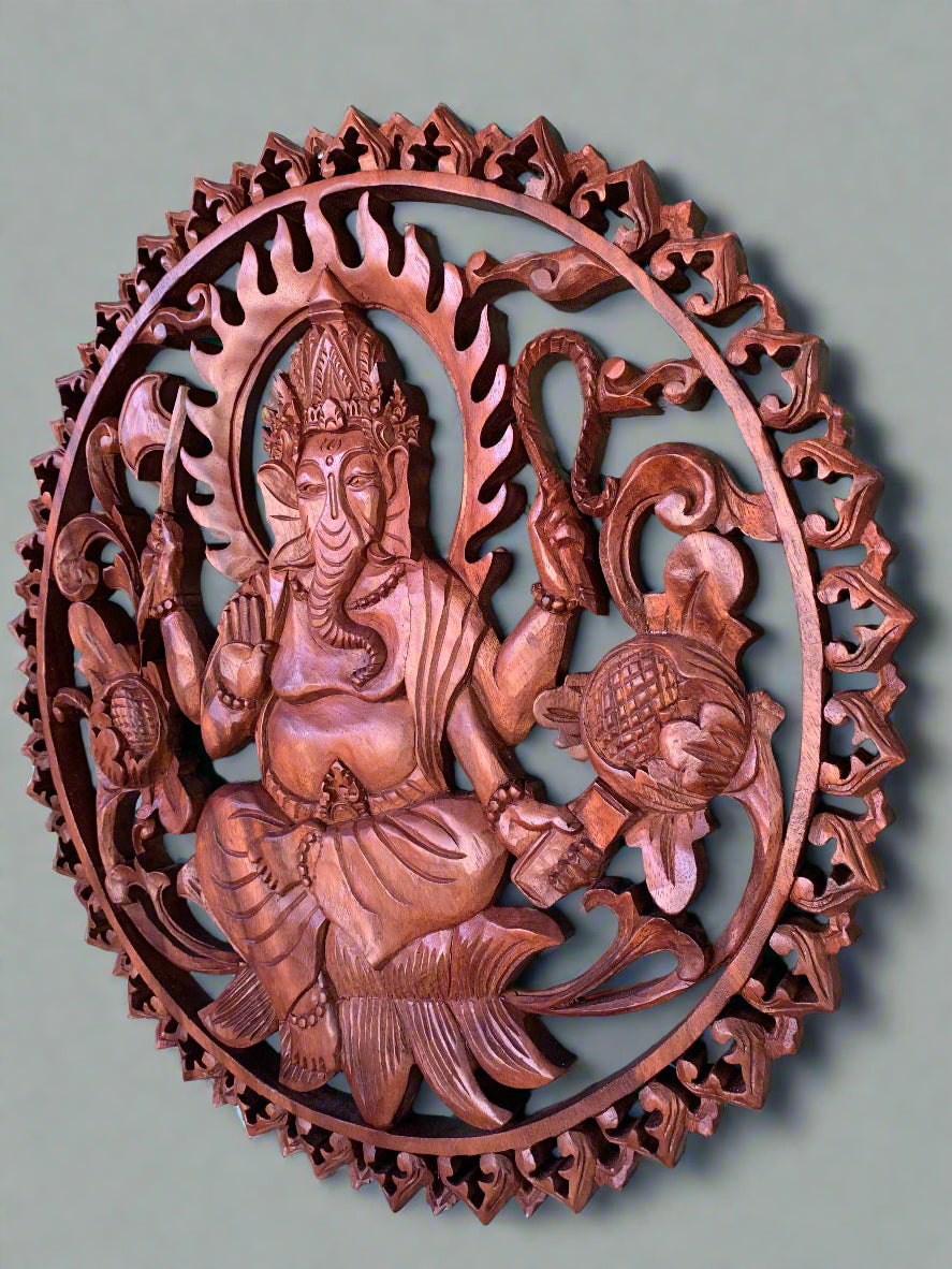 Round wooden carving of Ganesha deity with decorative flame border