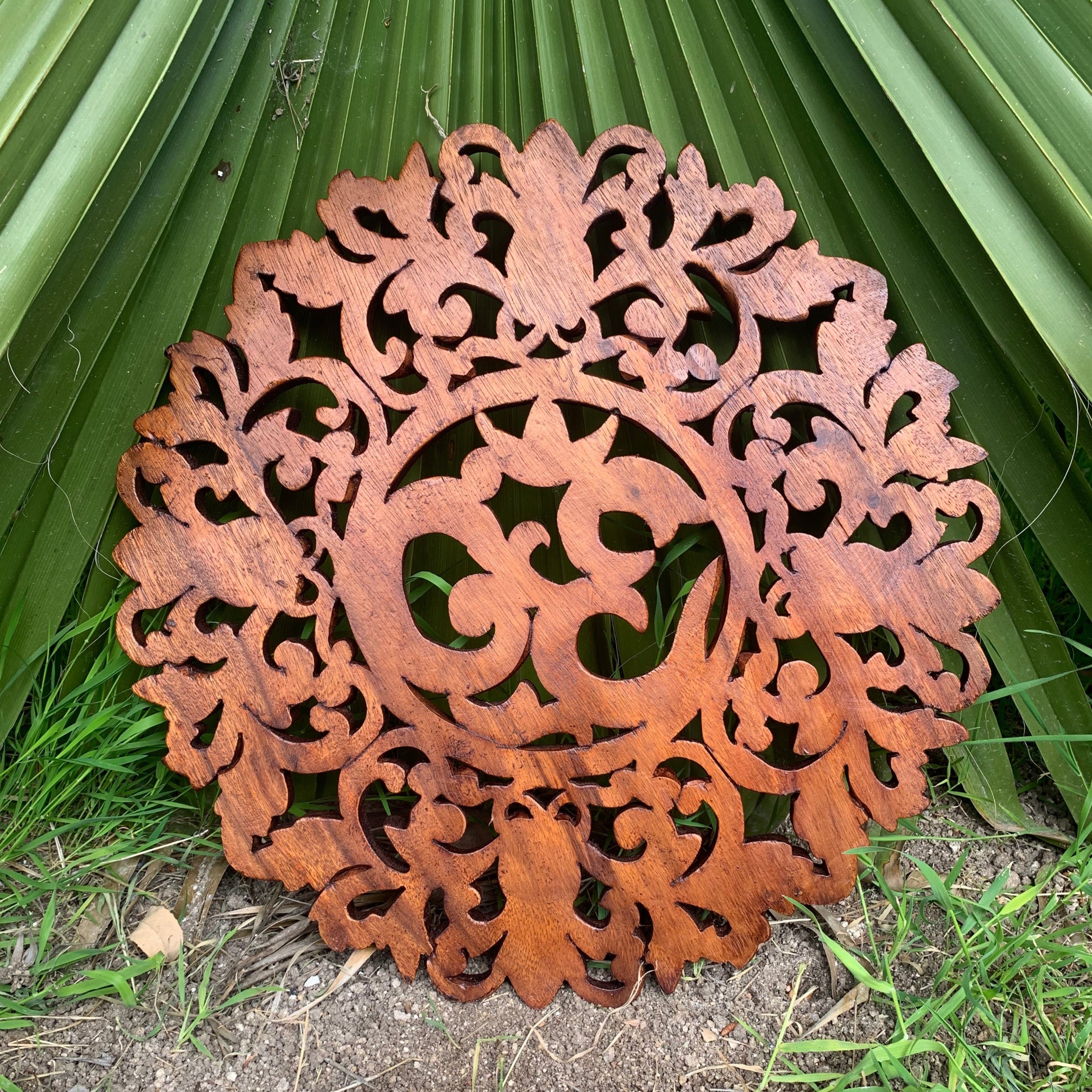 rusted metal mandala decorative plaque resting on green leaves