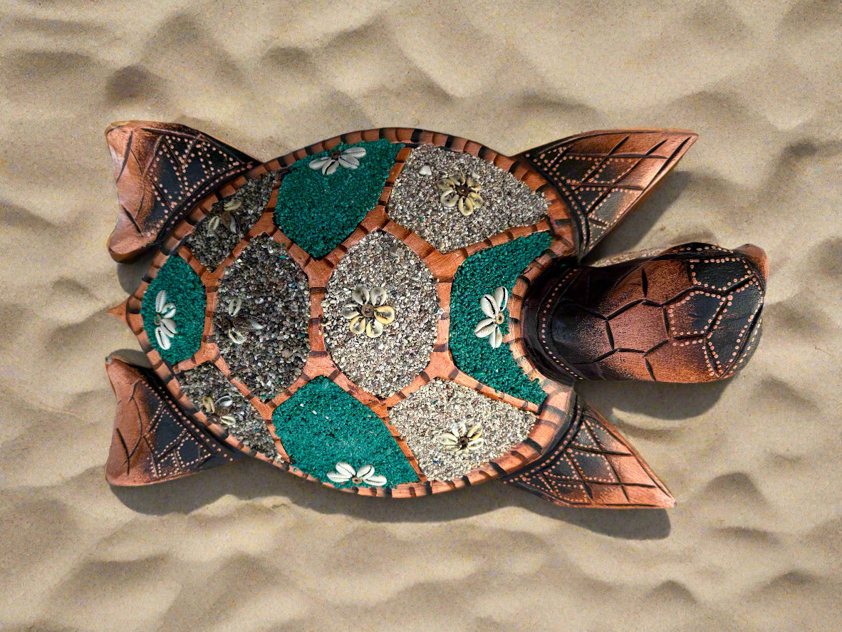 Decorative turtle mosaic on sand with teal and gray pebble sections and shell patterns.