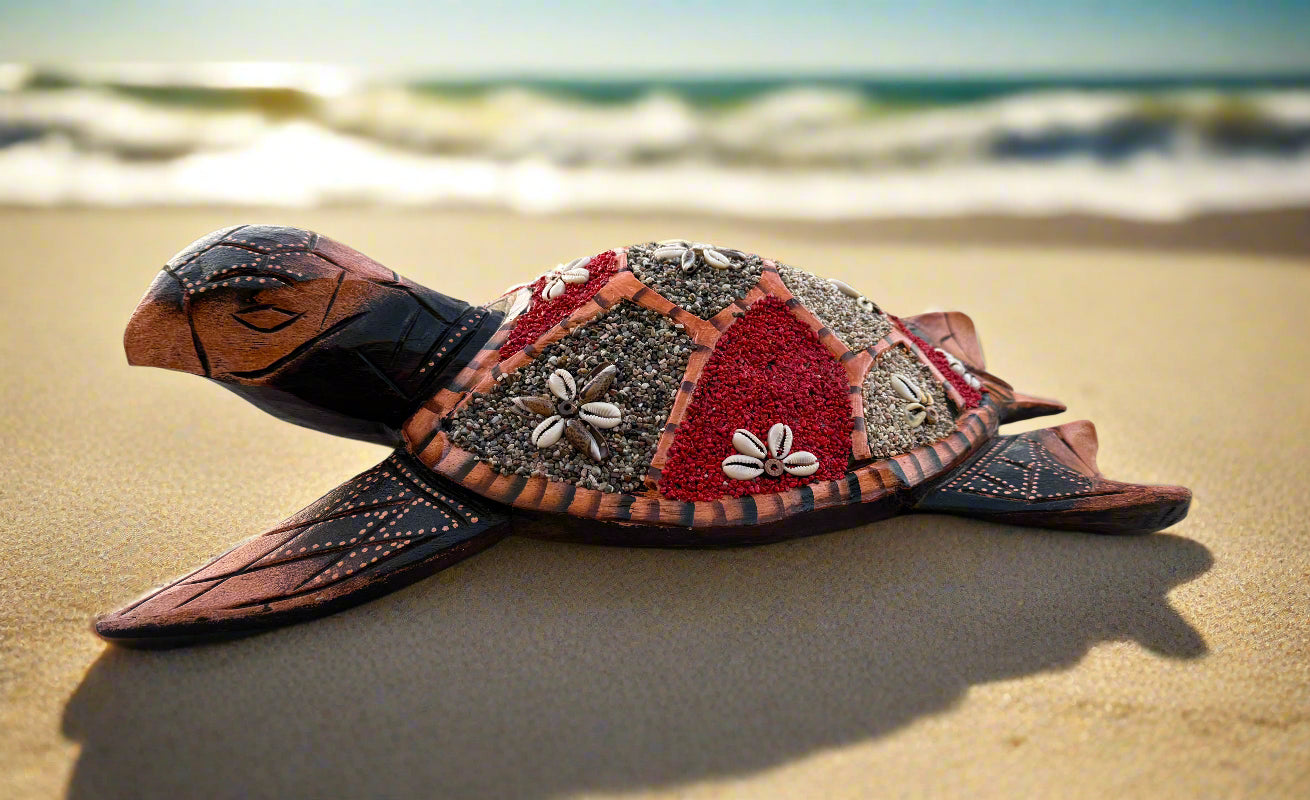 Decorative wooden sea turtle sculpture with shell decorations on a sandy beach