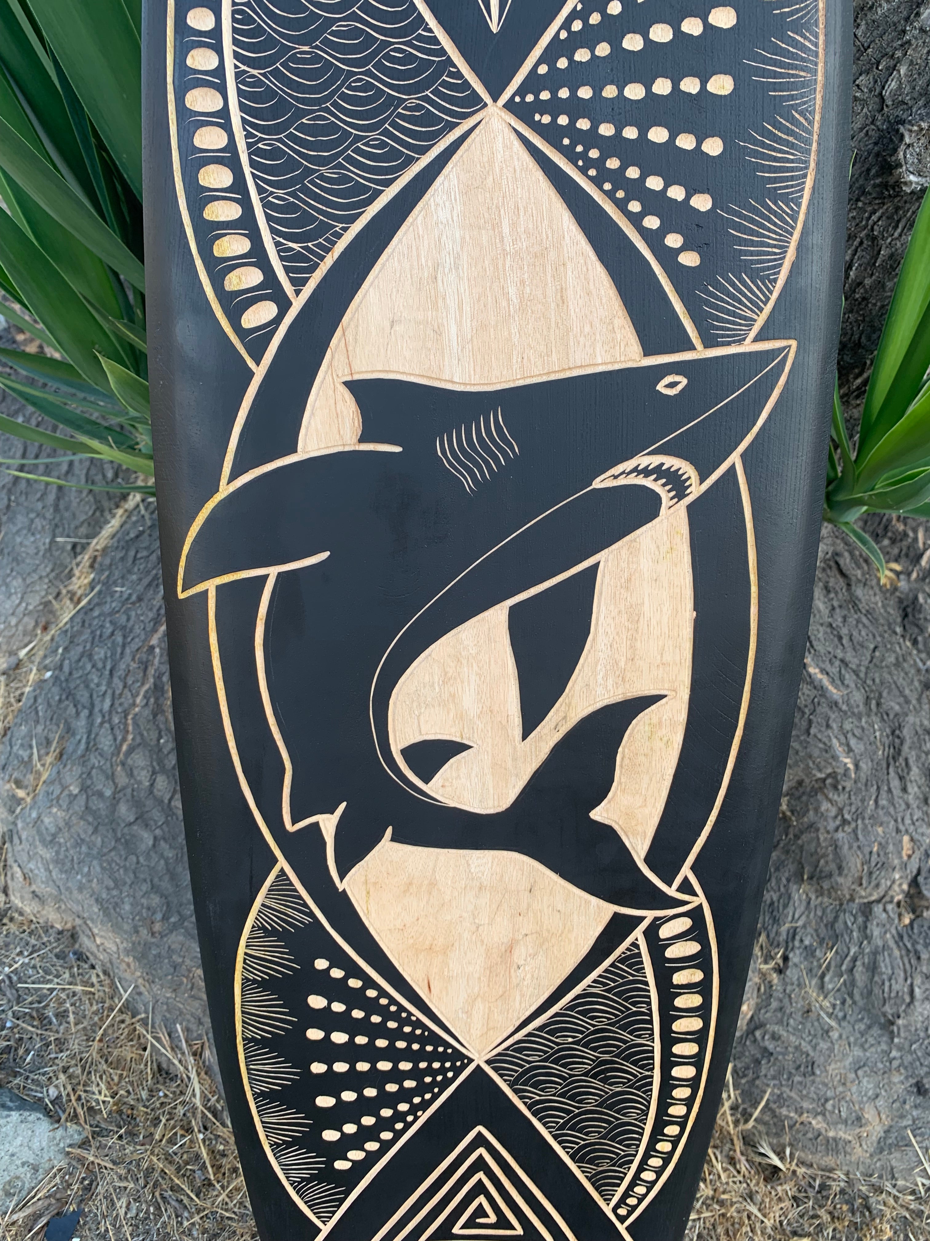 Shark carving on black and natural wood panel with circular geometric patterns