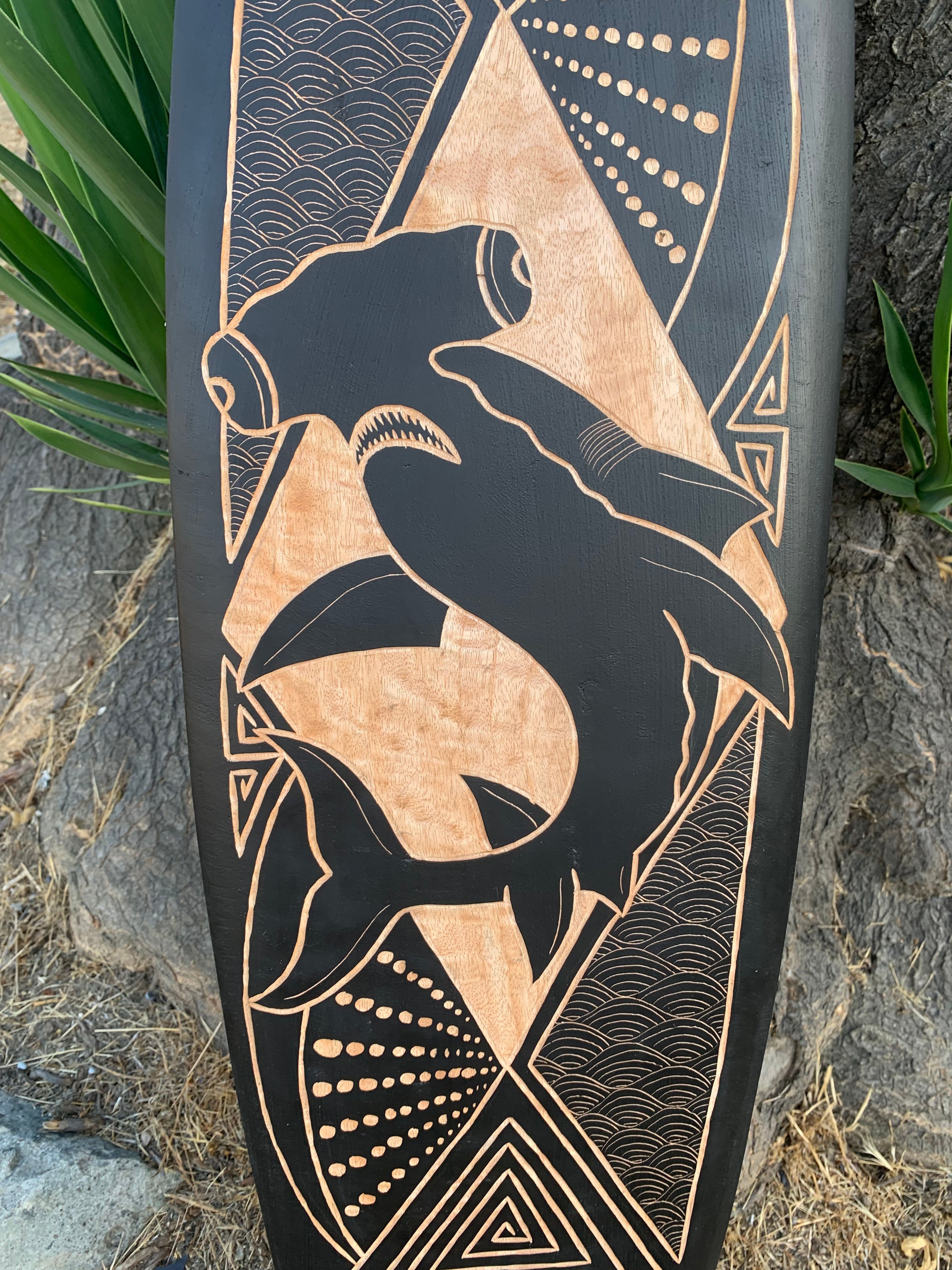 Stylized carved wooden panel featuring a dolphin motif with geometric and wave patterns.