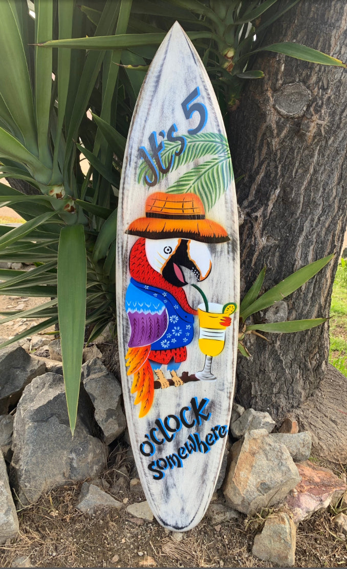 Colorful parrot on a weathered surfboard with a tropical drink and O'Clock Somewhere text