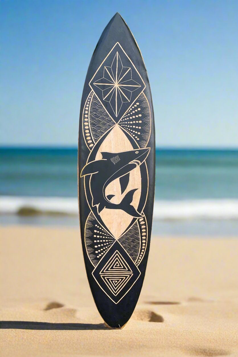 Surfboard on beach featuring a geometric shark design