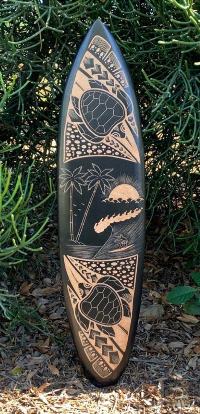 surfboard standing upright with Polynesian-inspired tribal art featuring turtle, palm trees, sun and geometric patterns