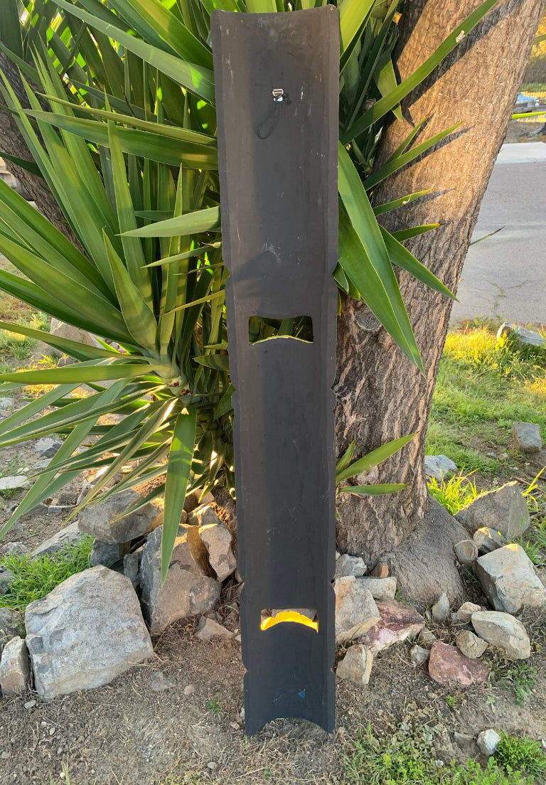 tall black rectangular panel with two cutouts leaning against a tree outdoors