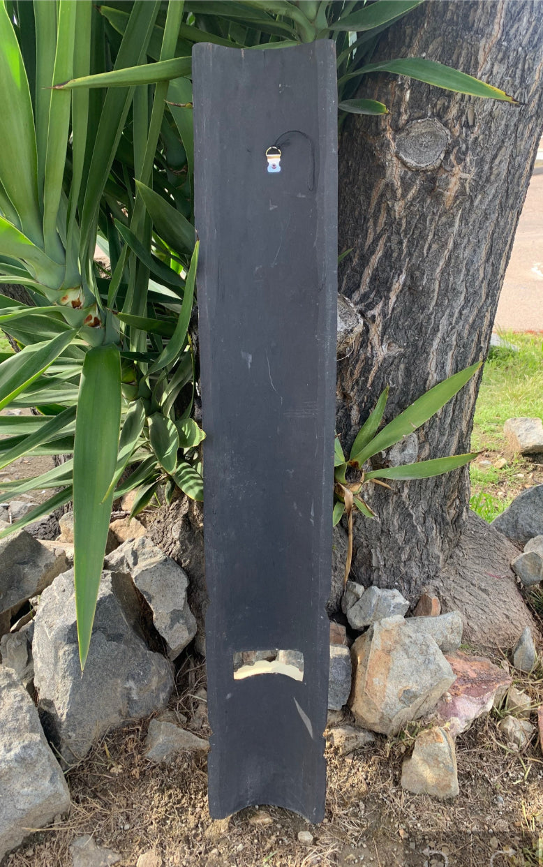 Tall black wooden board leaning against a tree with a small padlock attached