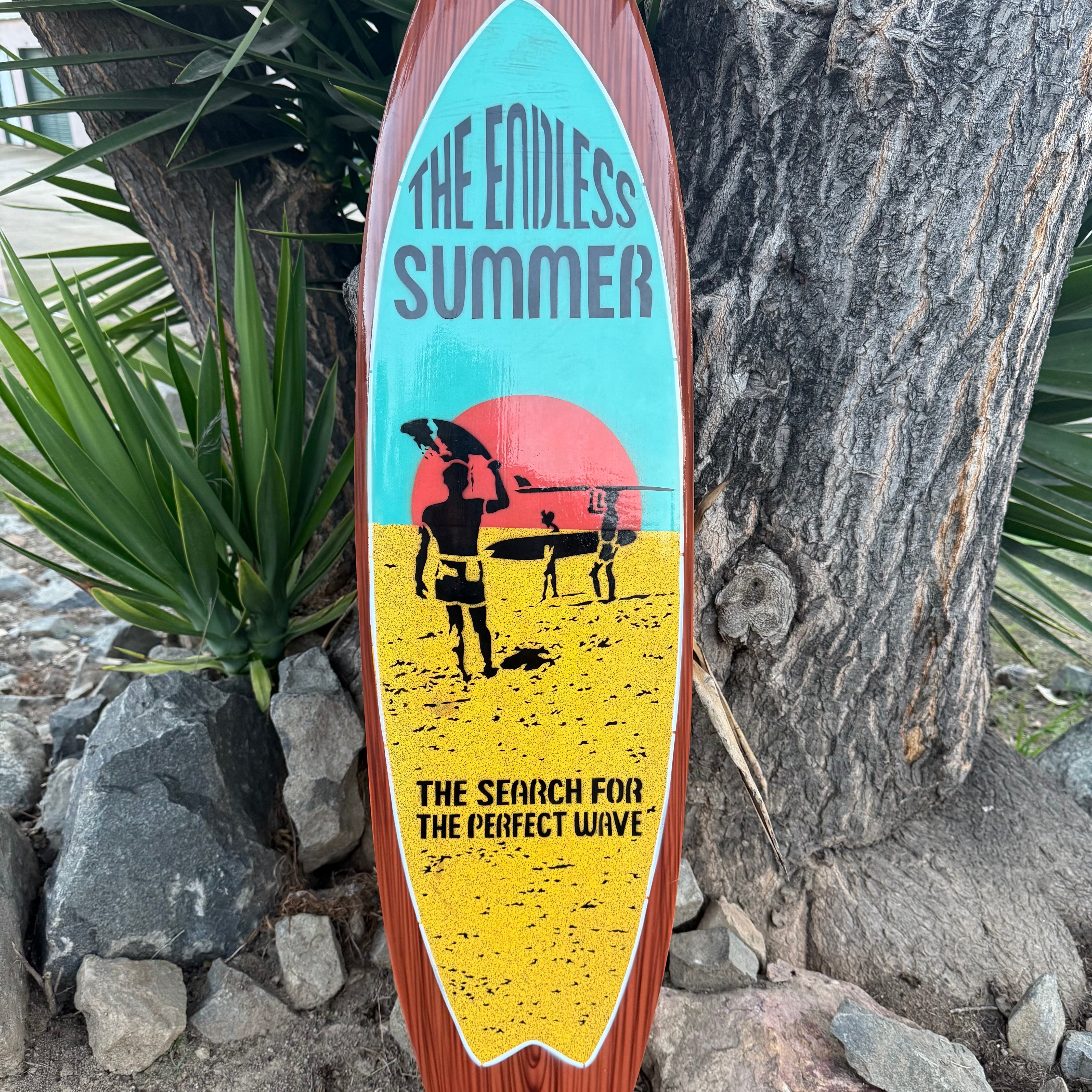 Surfboard with 'The Endless Summer' design leaning against a tree