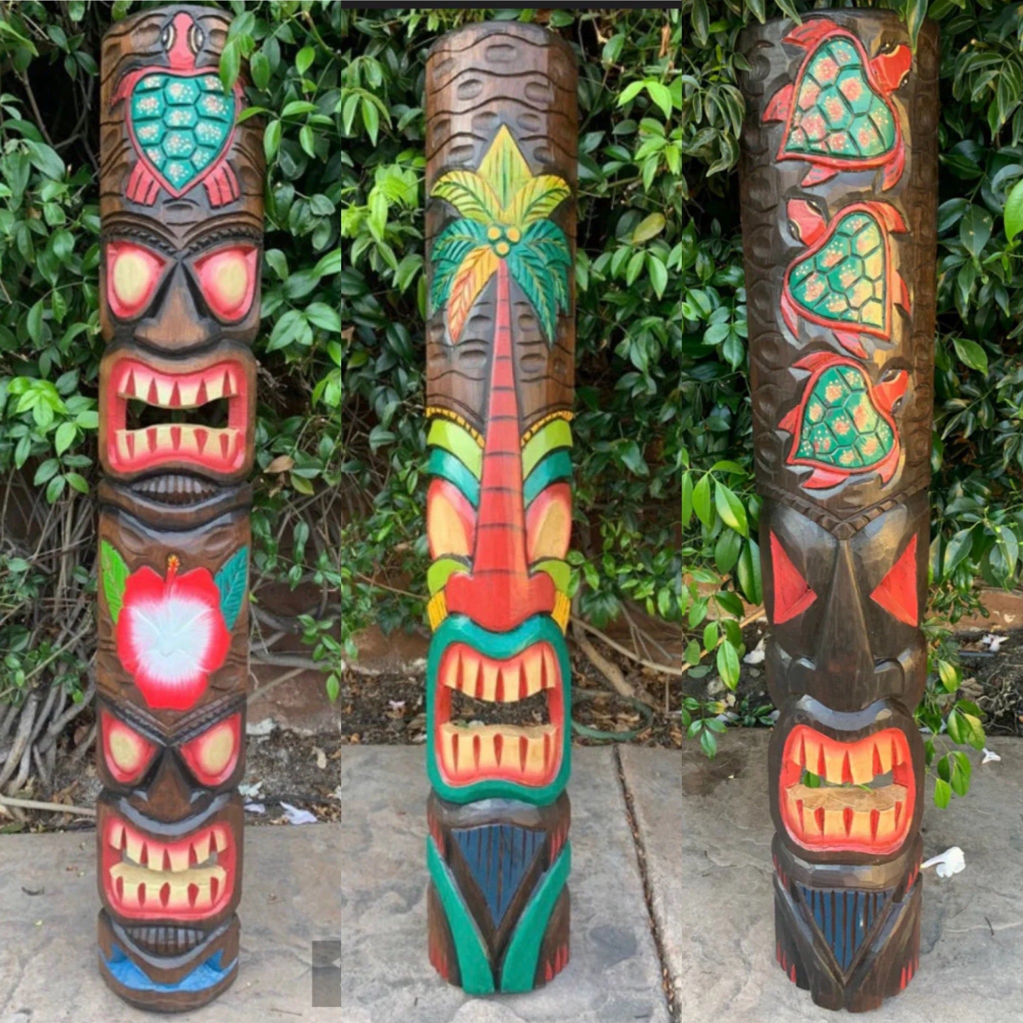 Three colorful tiki totem poles with carved faces and palm-tree patterns against greenery.