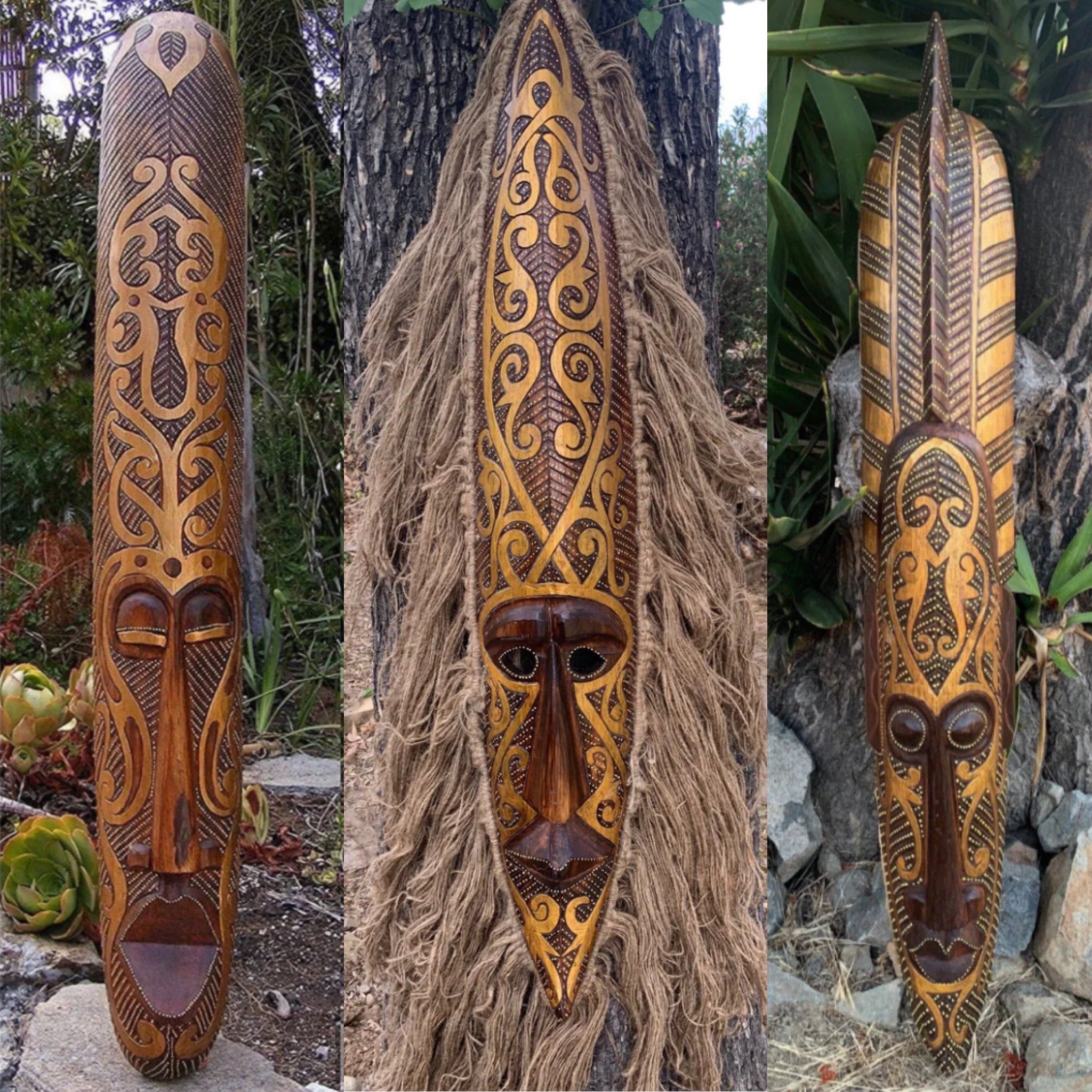 Three tall carved wooden masks with intricate gold-toned patterns displayed outdoors.