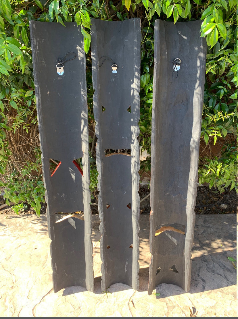 Three tall slate panels with triangular cutouts arranged outdoors near greenery.
