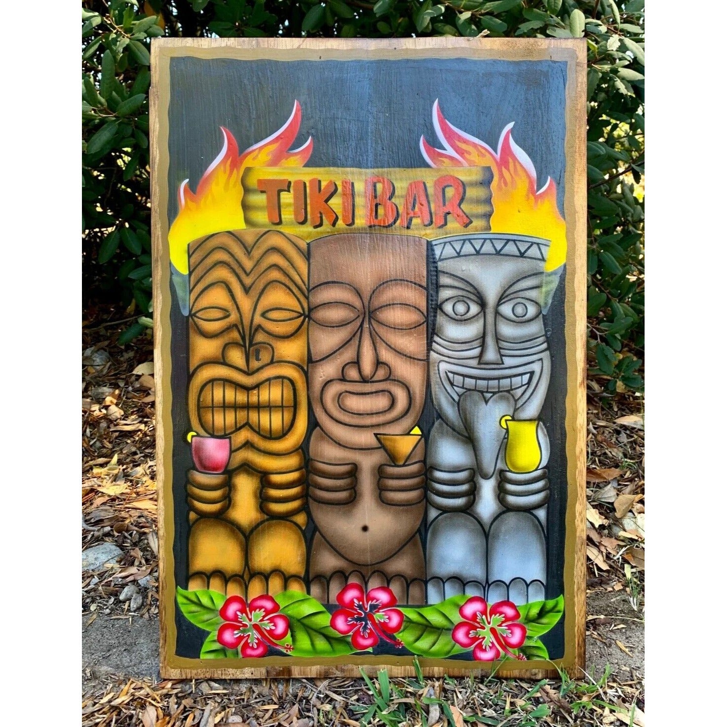 Three tiki masks with drinks under a flaming tiki-bar sign, tropical flowers border the bottom.
