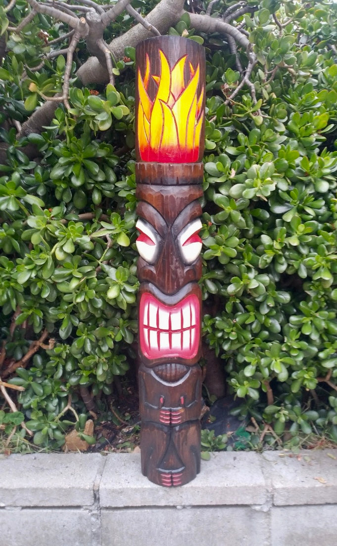 carved wooden tiki totem with flame design on top