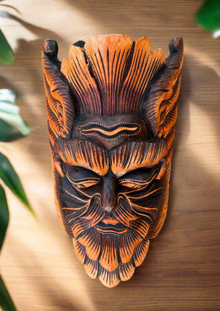 Carved wooden tiki mask with bold orange and black patterns and closed eyes