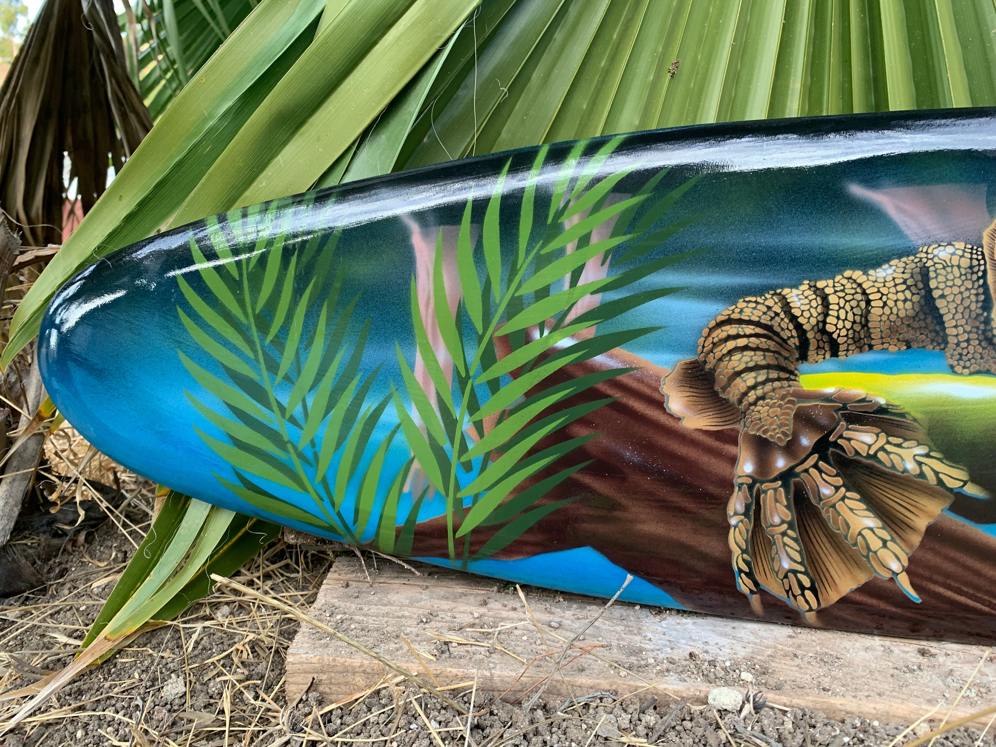 Painted surfboard with tropical palm leaves and an alligator illustration