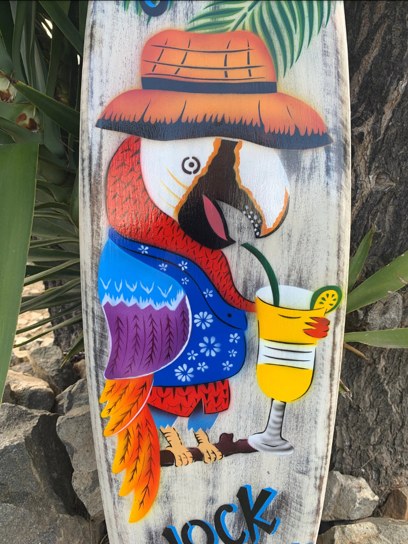 Colorful parrot wearing a wide-brimmed hat, sipping a yellow cocktail on weathered wood.