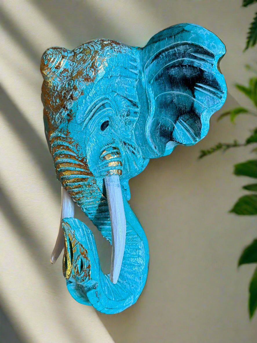 Turquoise-blue elephant head sculpture with a curling trunk