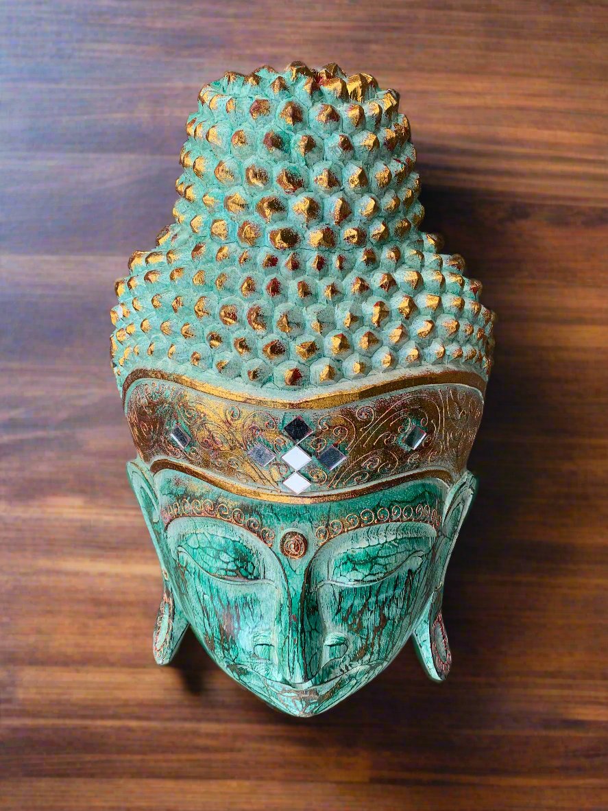Turquoise Buddha head sculpture with ornate gold details on a wooden background