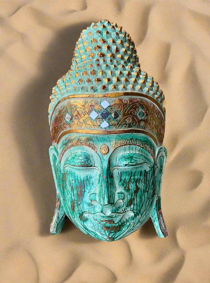 Turquoise Buddha head sculpture with an ornate crown and diamond-like inlays on a sandy background