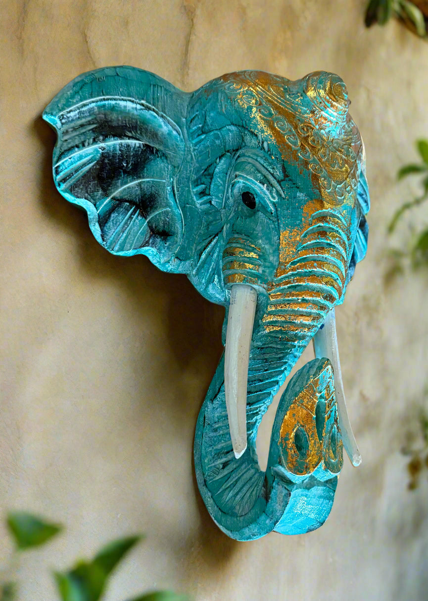 Turquoise wall-mounted elephant head sculpture with gold detailing and white tusks.