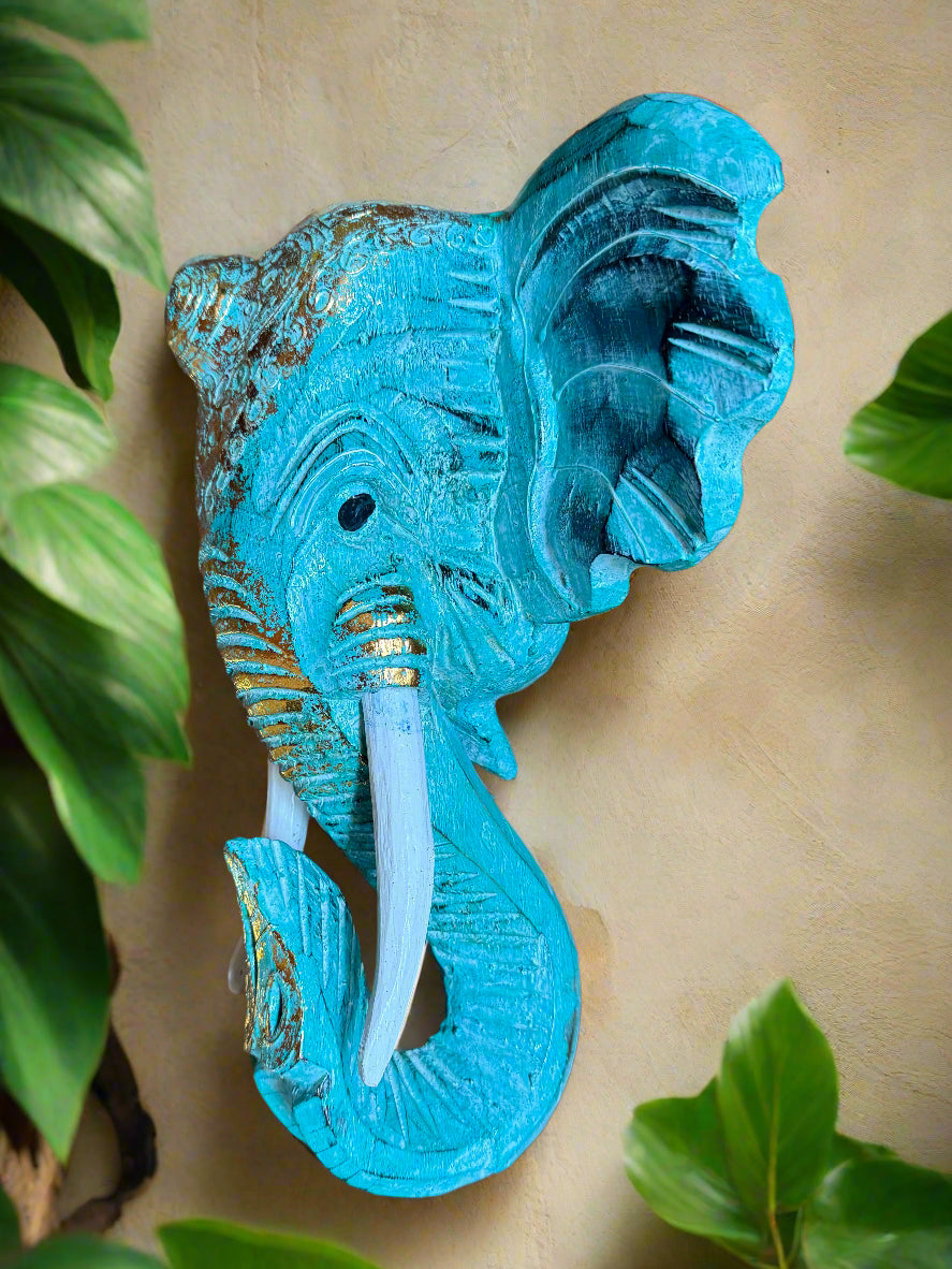 turquoise elephant wall sculpture with carved trunk and green leaves