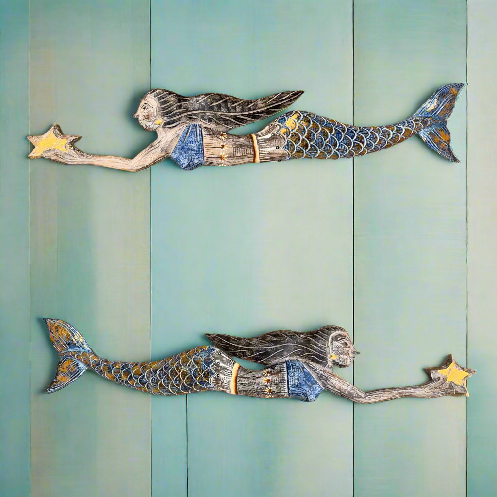 Two mermaids reaching for stars on a teal wood panel wall, whimsical sea-inspired wall art.
