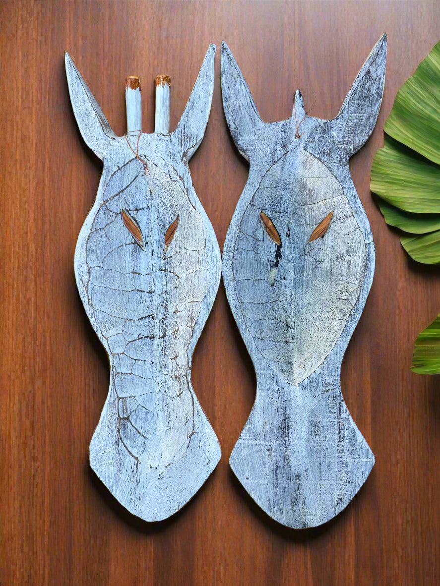 Two distressed blue wooden giraffe silhouettes mounted on a wooden wall