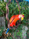 Colorful wooden parrot sculpture hanging on vines in a garden